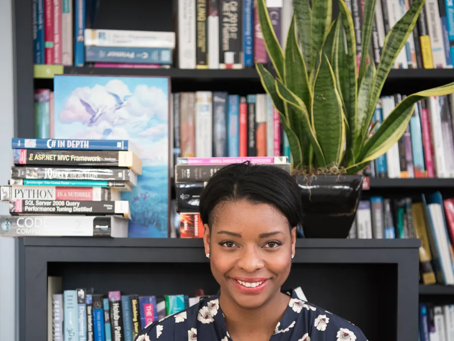 Étudiante souriante devant sa bibliothèque